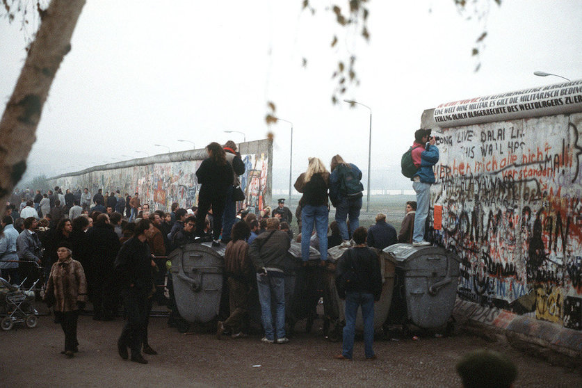 Berlineses cruzando el muro por los huecos recién abiertos.