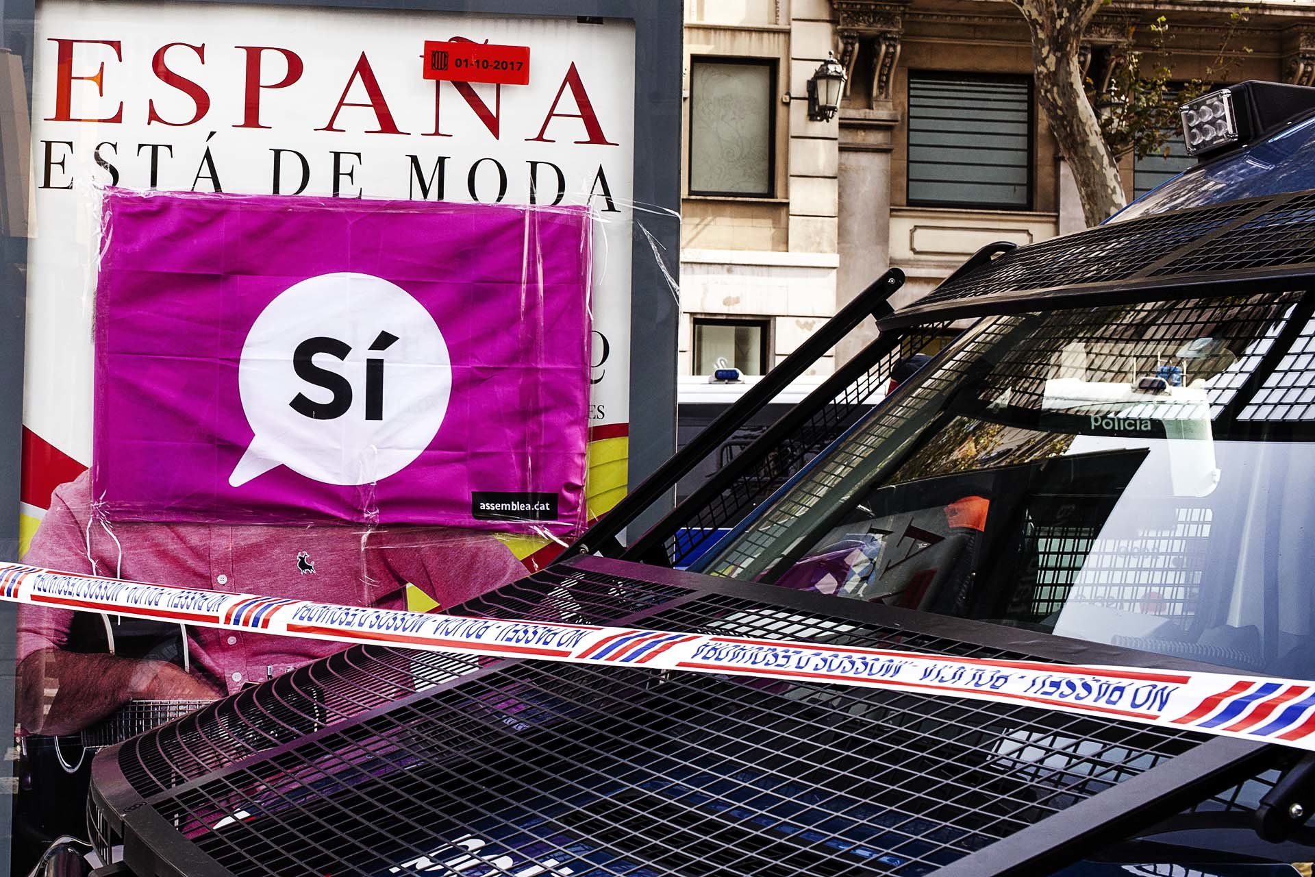 A vehicle of the Mossos de Esquadra, the Catalan autonomous police, before an advertising poster of a Spanish brand that says 